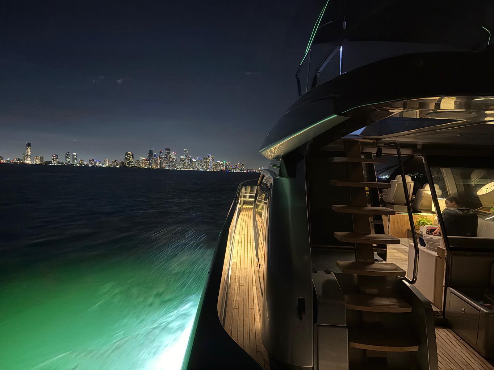 Yate Riva One of a Kind iluminado de noche frente al skyline de Miami